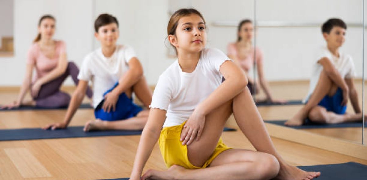 Tween girl exercising with brother, mother and father at yoga class, concept of healthy family lifestyle